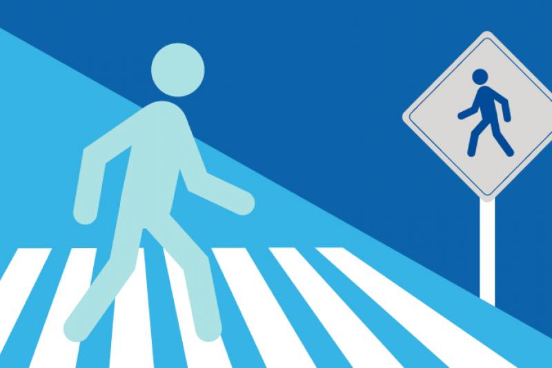 Decorative graphic of a person walking in a crosswalk