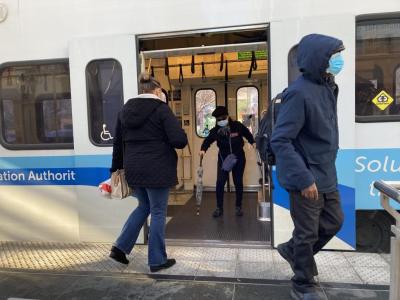 people getting on and off a light rail train
