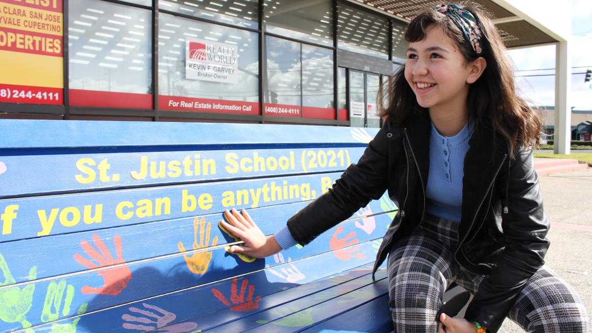 student poses at public art bench