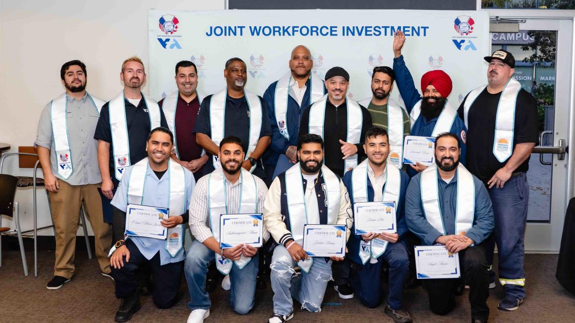 class of apprenticeship graduates pose with certificates