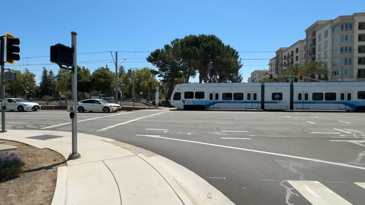 vehicle waiting at the light and VTA train on tracks