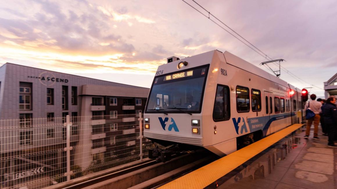 VTA light rail train driving on tracks next to a building