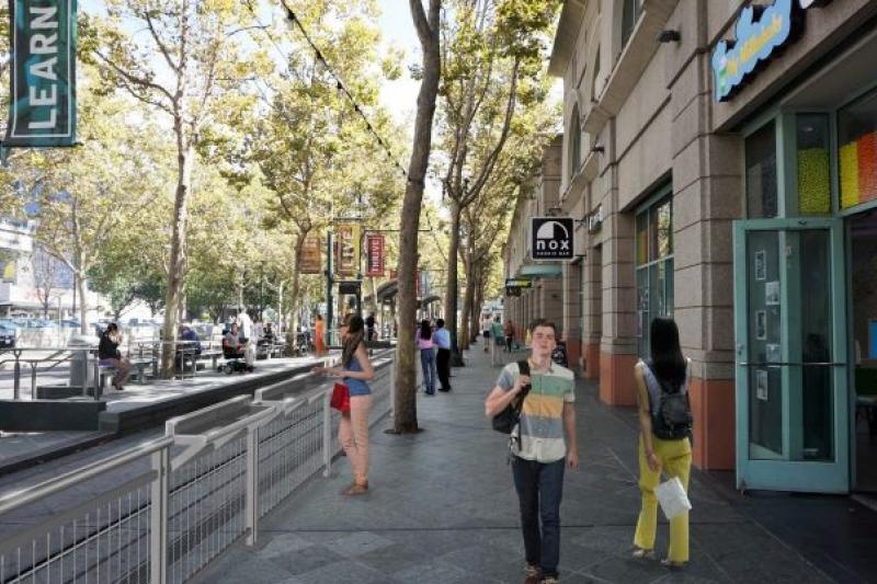 Image shows a rendering of the railing. and pedestrians walking on the sidewalk, between the railing and the businesses.