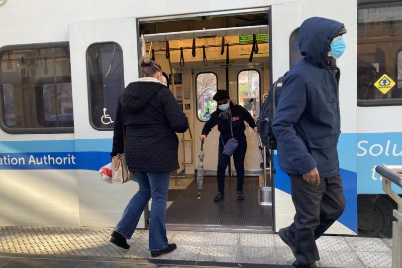 people getting on and off a light rail train