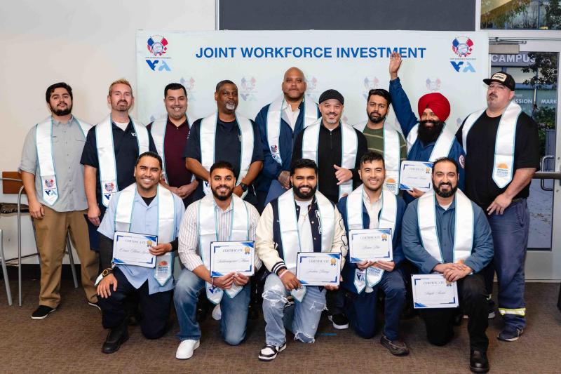 class of apprenticeship graduates pose with certificates