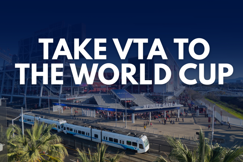 A VTA light rail train passes in front of Levi’s Stadium in Santa Clara with large white text over the image reading “Take VTA to the World Cup.” The stadium entrance and surrounding pedestrian areas are visible in the background under a blue overlay.