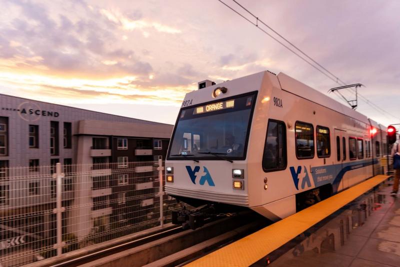 VTA light rail train driving on tracks next to a building