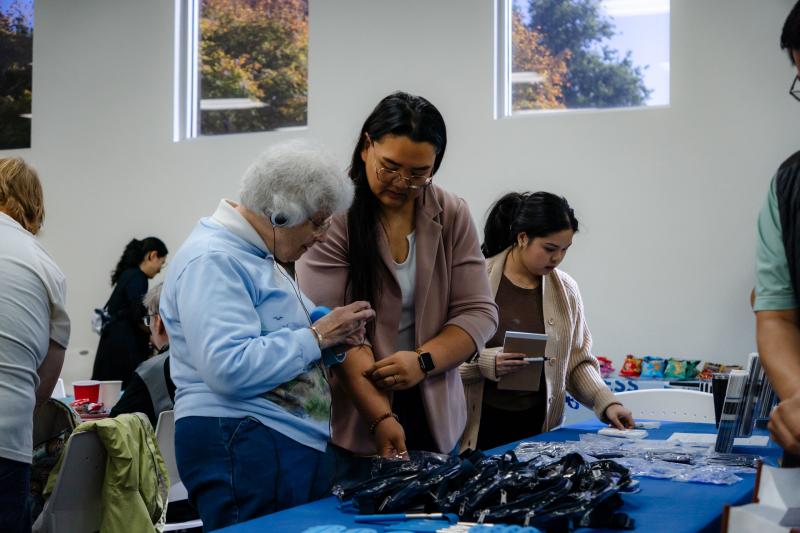 A VTA staff member assists a hearing-impaired attendee at a resource table during the Coffee with the Community event.