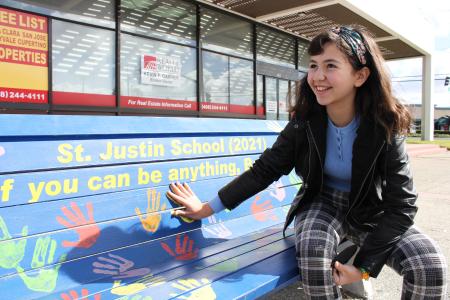 student poses at public art bench