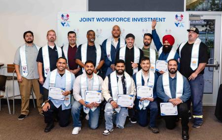 class of apprenticeship graduates pose with certificates