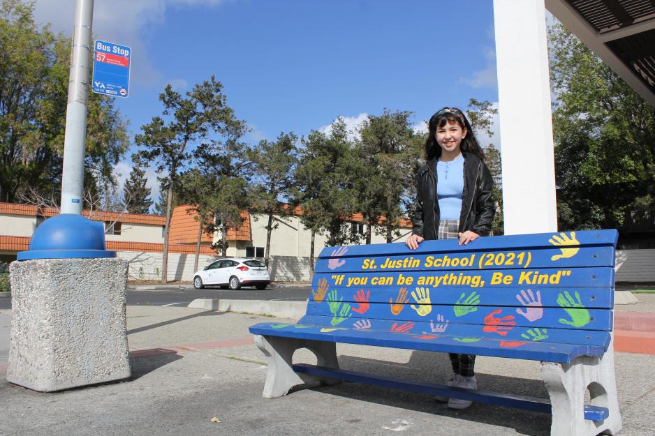 student poses next to public art bench