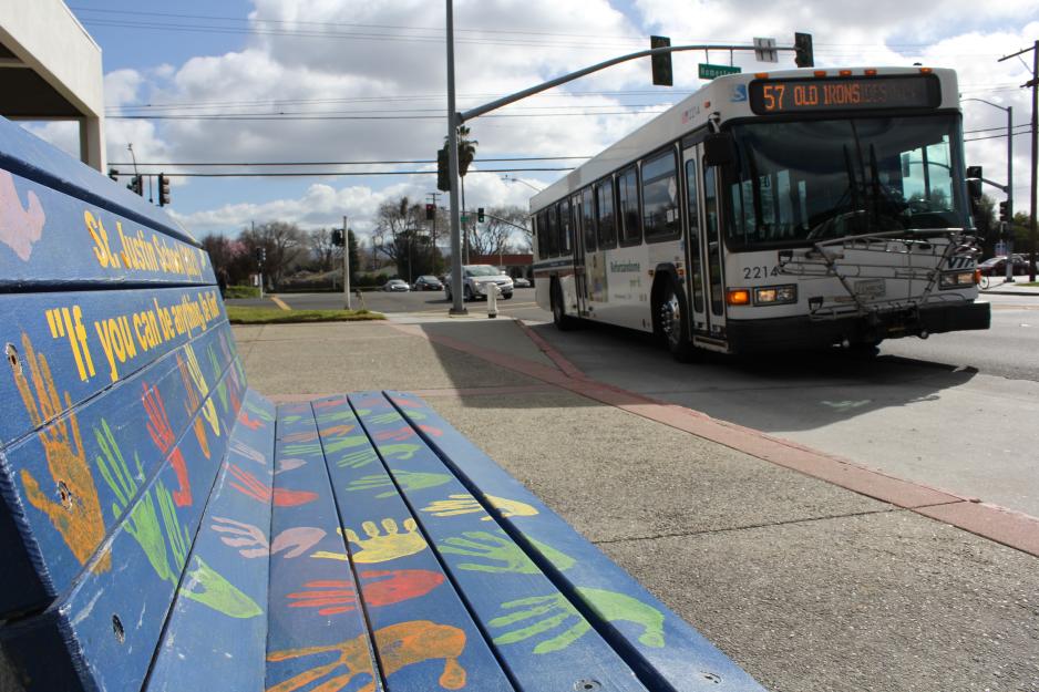 57 bus approaches bus stop with public art bench