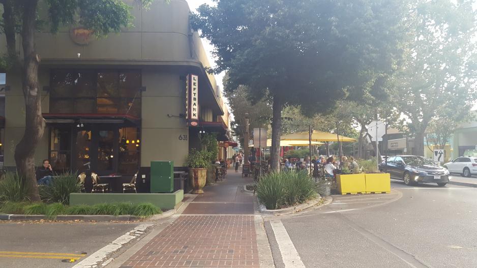 Photo of crosswalk and people sitting outside restaurant