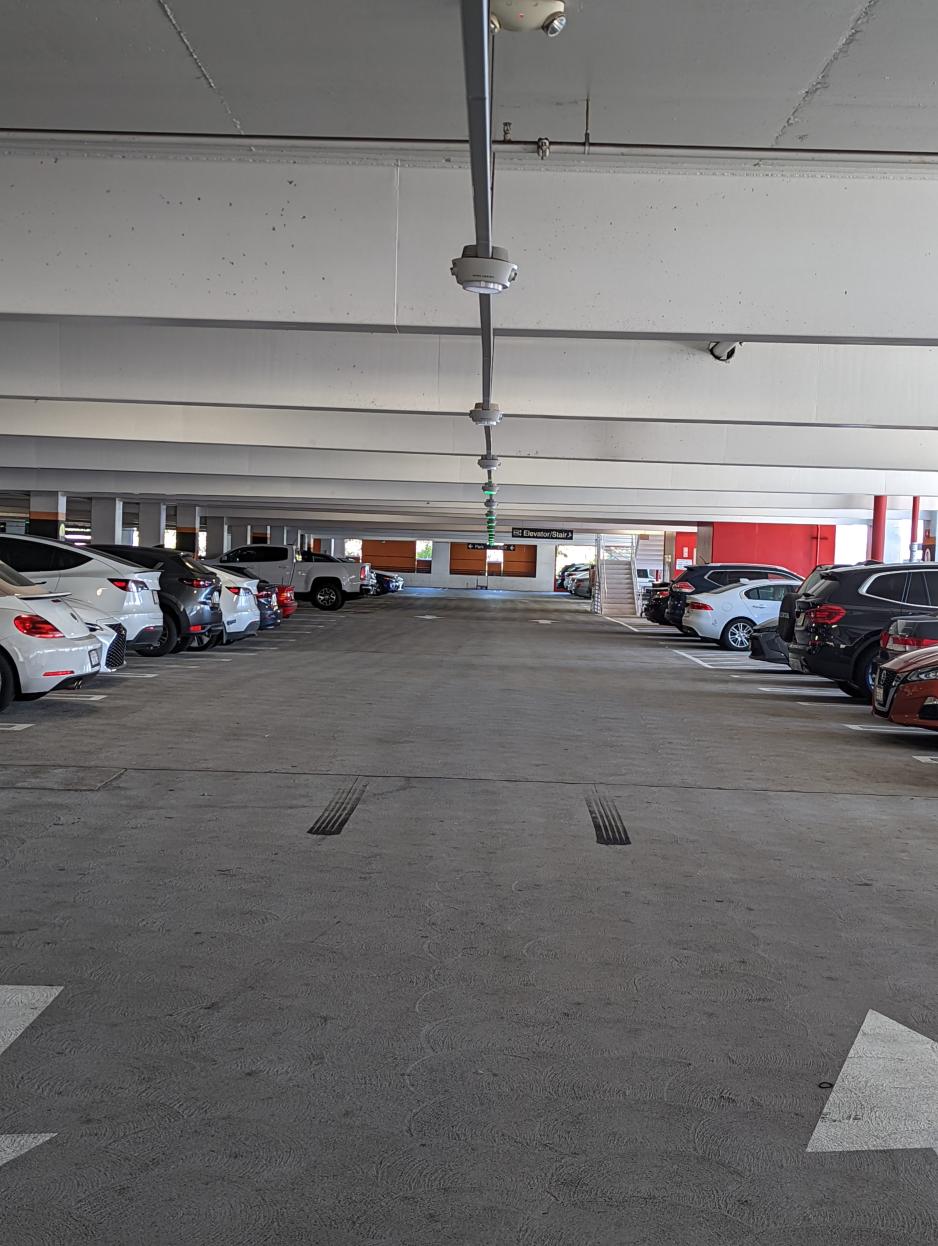 A photo of a parking structure with sensors in the center of the rows. When the light is green, the parking spot is available. 