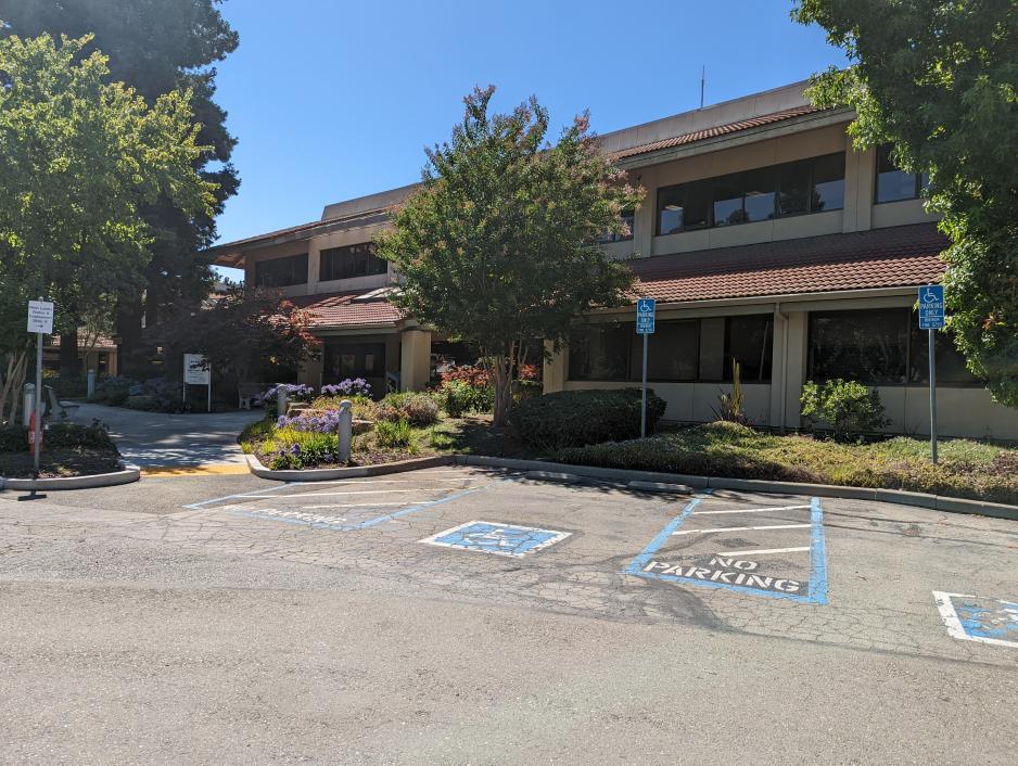 A photo of an ADA parking spot clear the entrance of an office building with an accessible curve connecting them. 