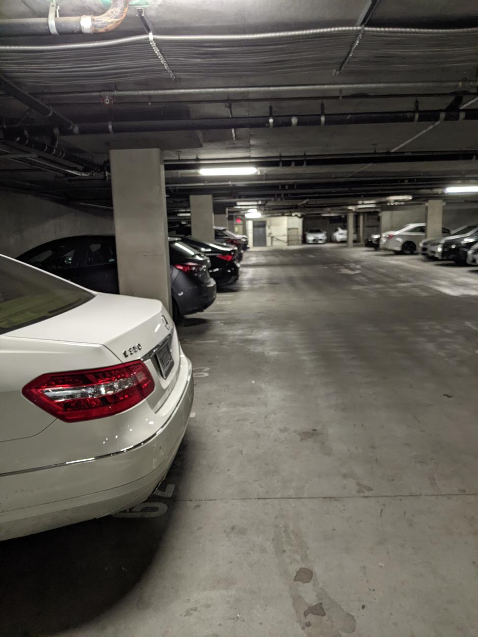 A photo of inside a parking garage with vehicle parking perpendicular to vehicle lanes.