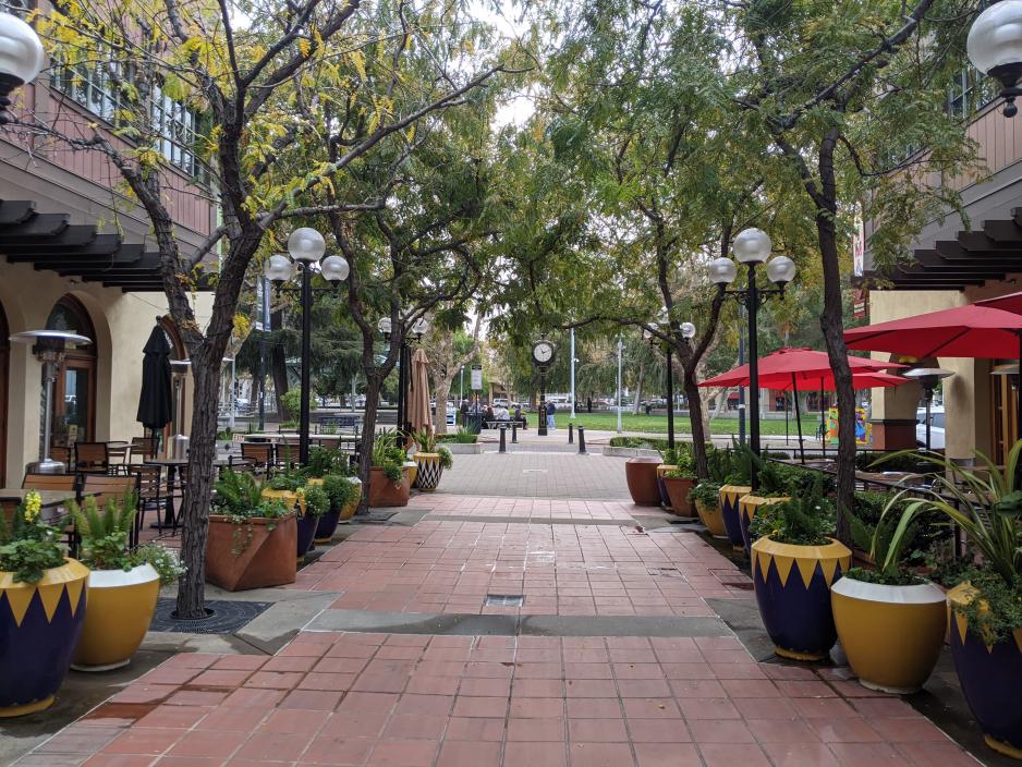 A photo of a pedestrian walkway between two restaurants with patio seating.