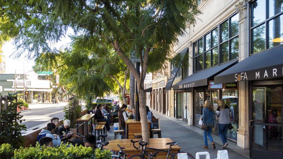 Photo of outside of cafe with people sitting and walking on the sidewalk