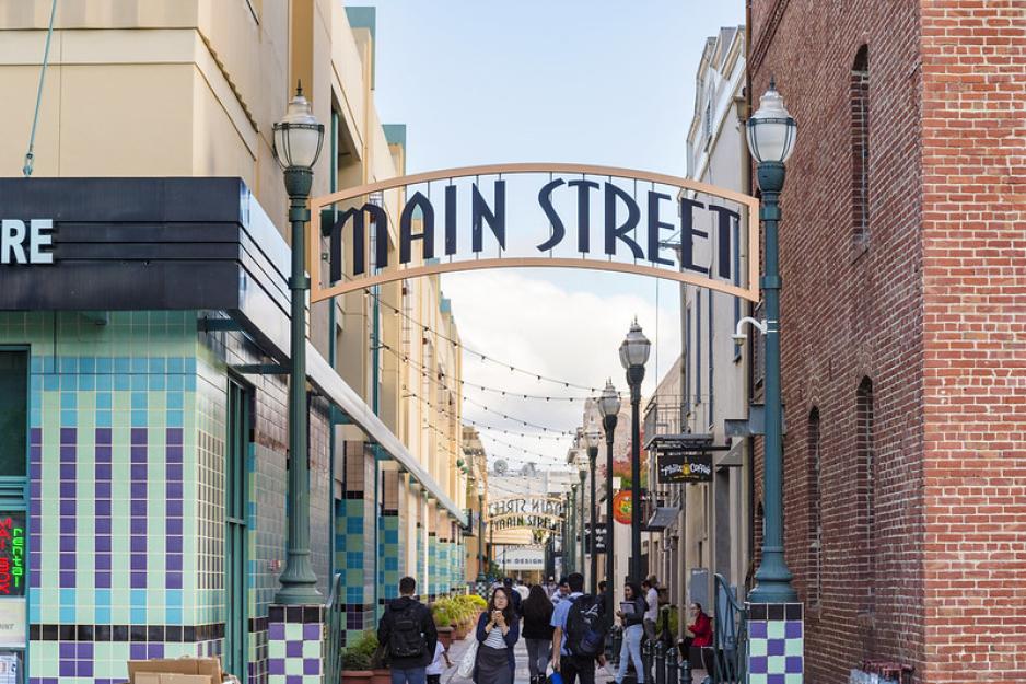 Photo of an alley with many pedestrians and an archway over the alley saying "Main Street."