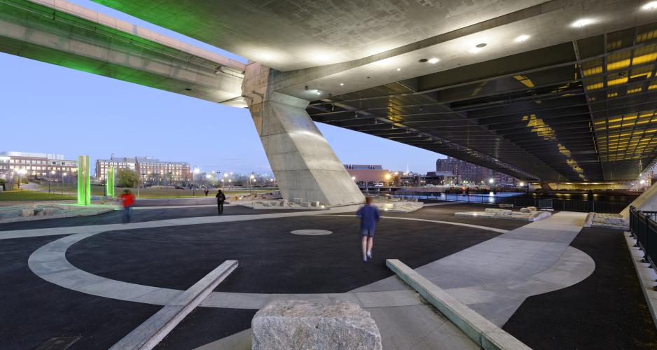 A photo of an urban plaza under an elevated roadway. 