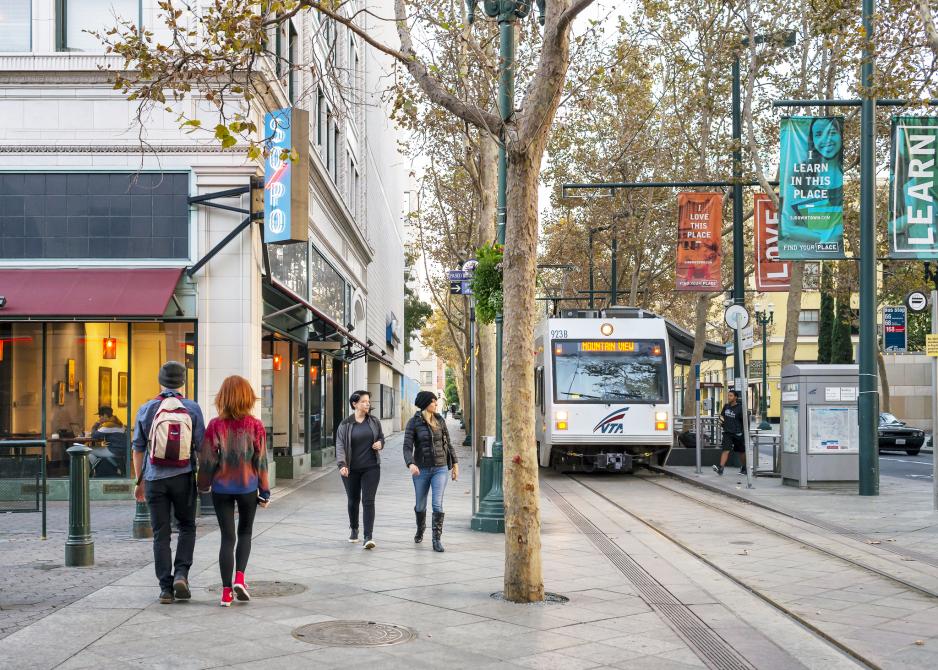 A photo of a light rail stop near businesses.