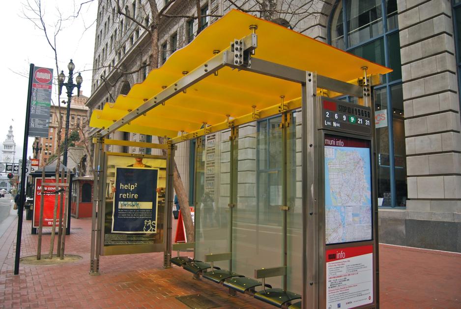 A photo of a bus shelter near commercial buildings.