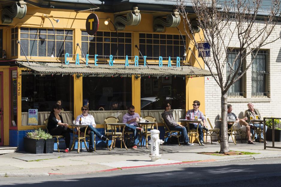 A photo of outdoor patio seating facing the street at a restaurant. 