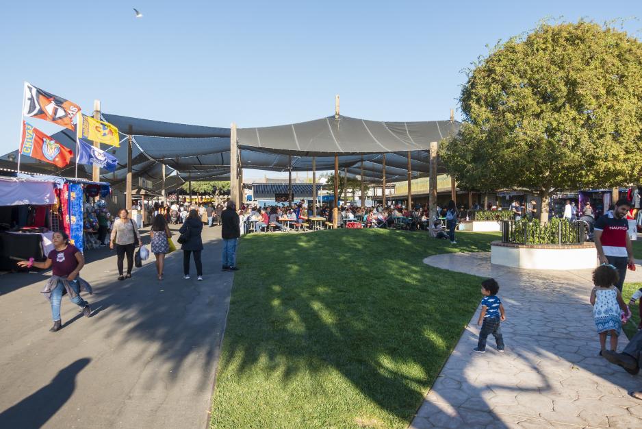 A photo of a small grass lawn with picnic tables with market booths.