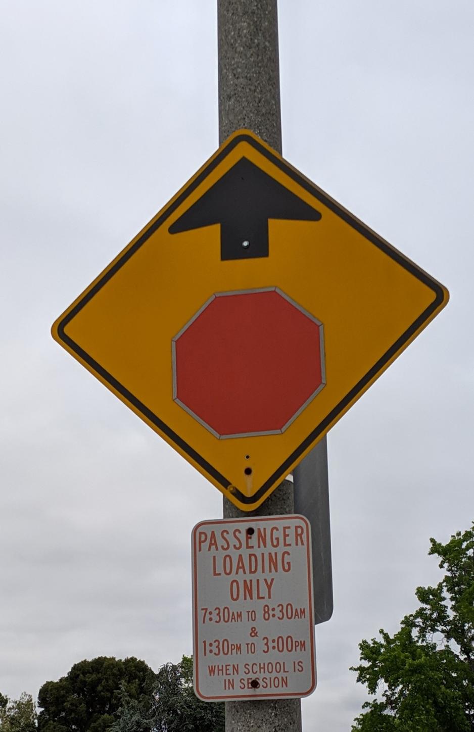 Photo of sign stating school loading times attached to a pole