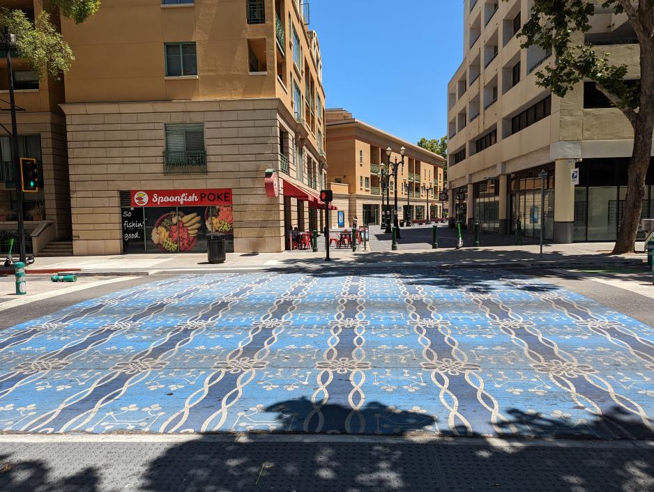 Photo of a colorful crosswalk for a pedestrian alleyway surrounded by taller buildings