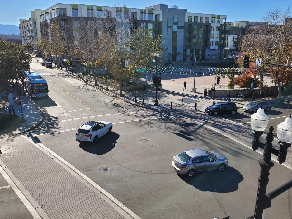 Photo of intersection by pedestrian plaza with bus waiting and cars traveling through