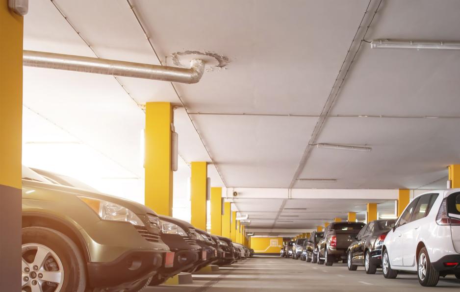 Photo of a parking garage with several cars parked on both sides of an aisle