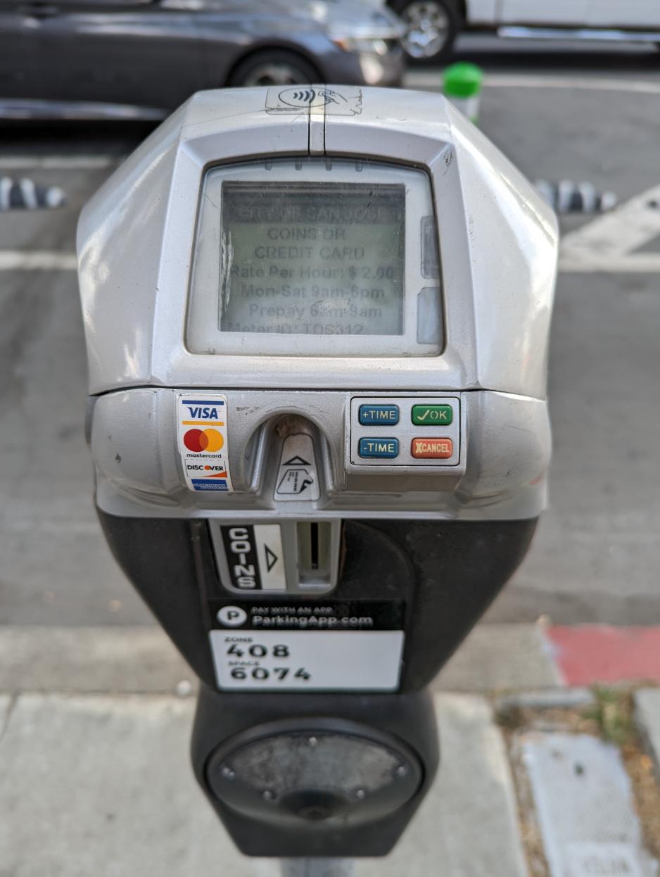 Photo of the front of a parking meter with bicycle lane and parked vehicle behind