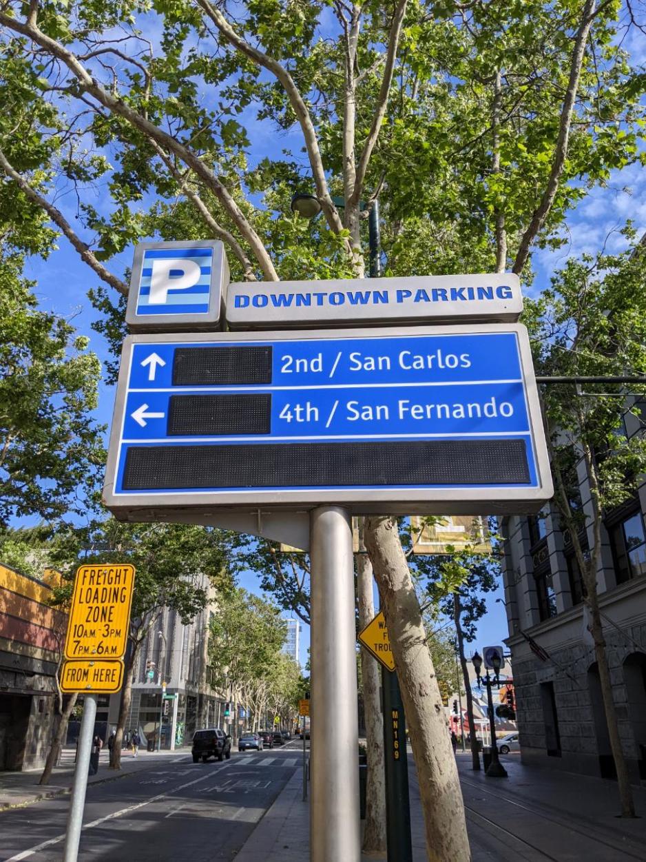 Photo of digital sign that is off but is supposed to show how many parking spaces are available in nearby parking garages in front of trees