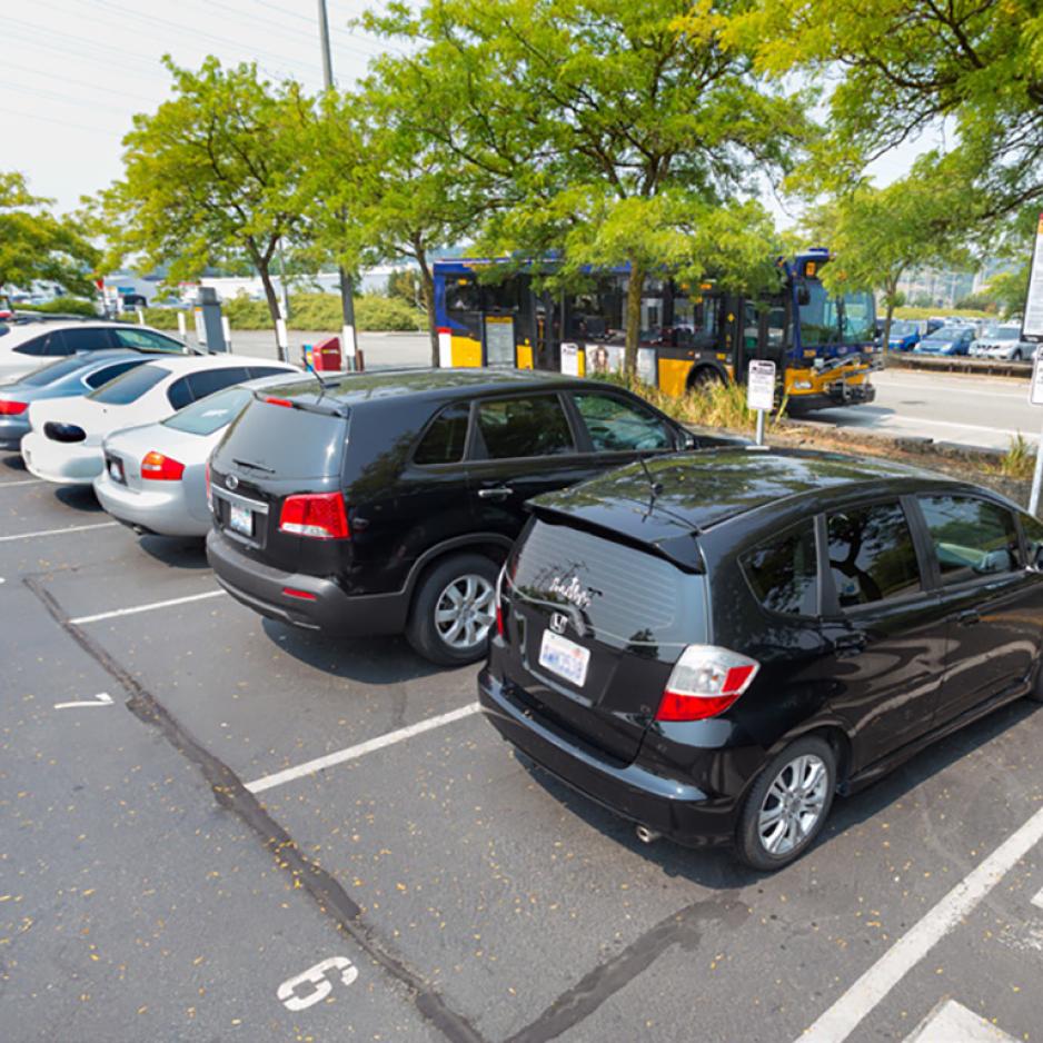 Photo of cars parked in carpool spaces with trees and a bus behind