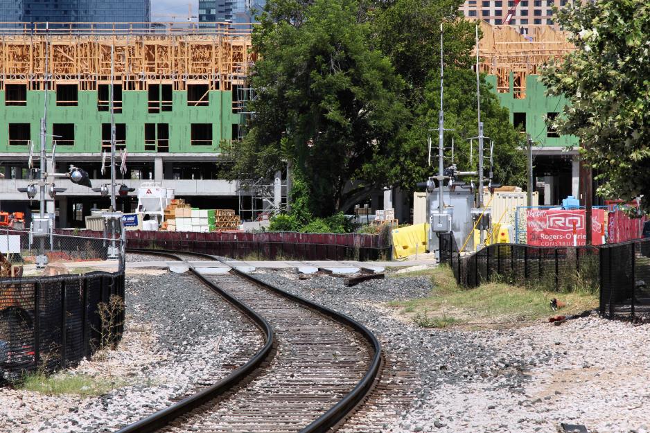 Photo of railroad tracks and crossing with building under construction in the background