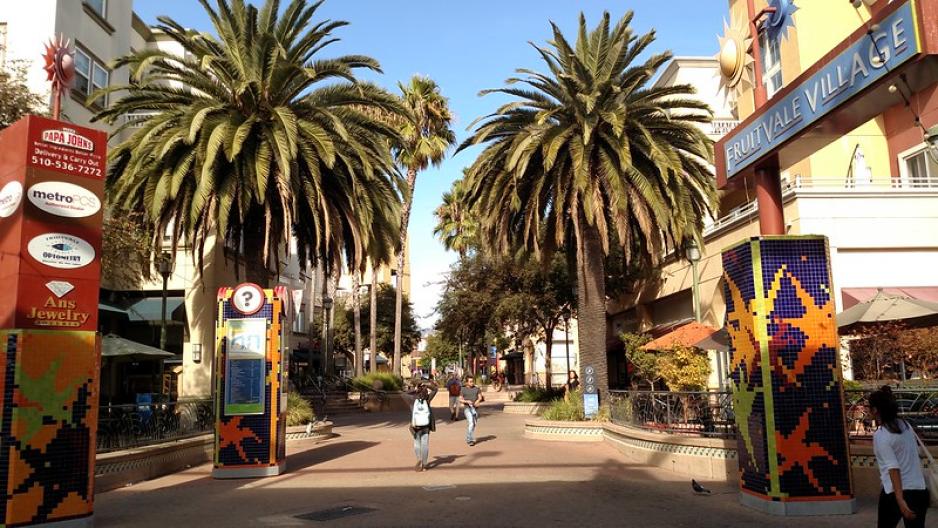 Photo of pedestrian walkway with palm trees and signage and advertising kiosks