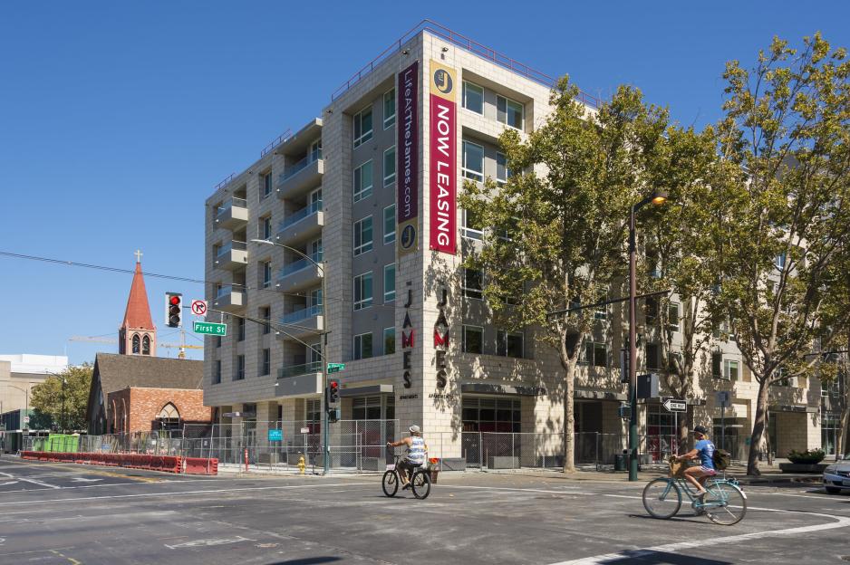 Photo of taller building under construction with two bicyclists traveling in front