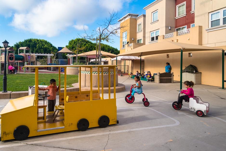 Photo of children playing and riding tricycles at a playground 