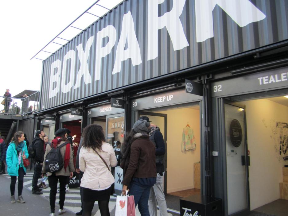 Photo of shop entrances made out of old shipping containers with shoppers walking