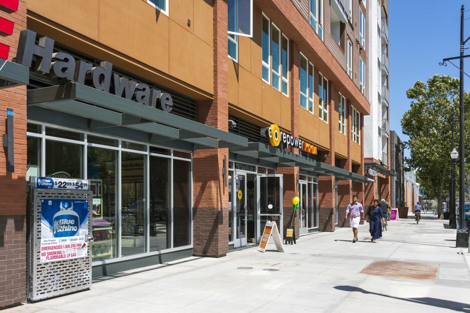 Photo of entrances to several shops in a row with pedestrians walking