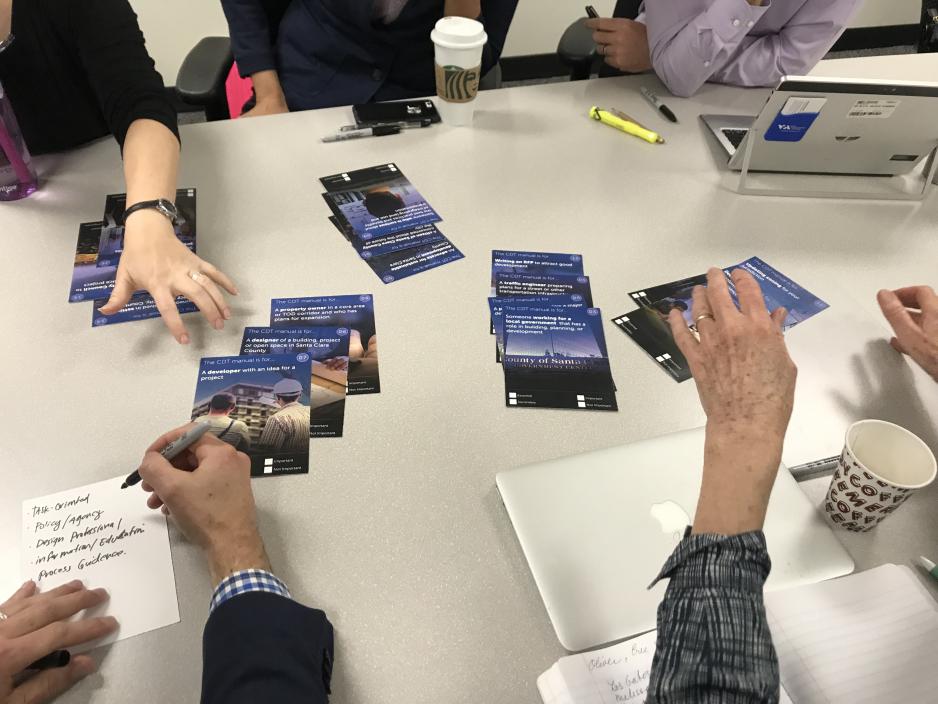 A photo of a table with people writing ideas and flyers for the CDT Manual. 