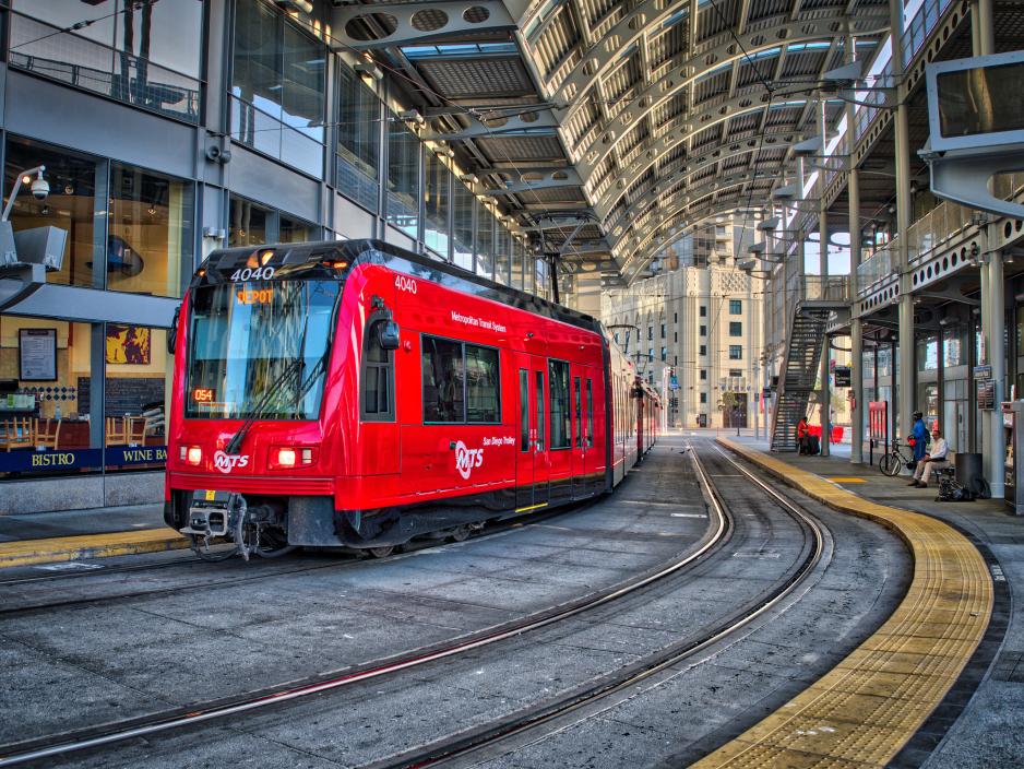 A photo of a train through a commerical area.