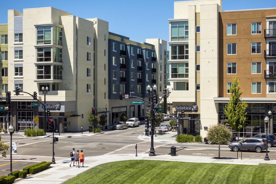 A photo of mixed-use buildings next to a park and wide sidewalks.