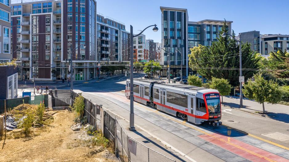 A photo of light rail traveling with high-rises in the background.