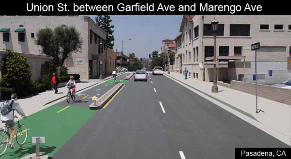 Graphic of an artists rendering of a redesigned roadway with a two-way separated bikeway on the left side and two-lane roadway on the right with buildings on either side and people walking and biking