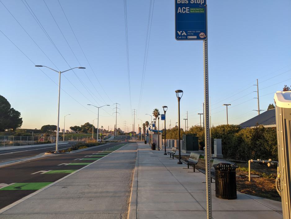 Photo of a VTA bus stop with a dashed bike lane to the left of the concrete bus pad.