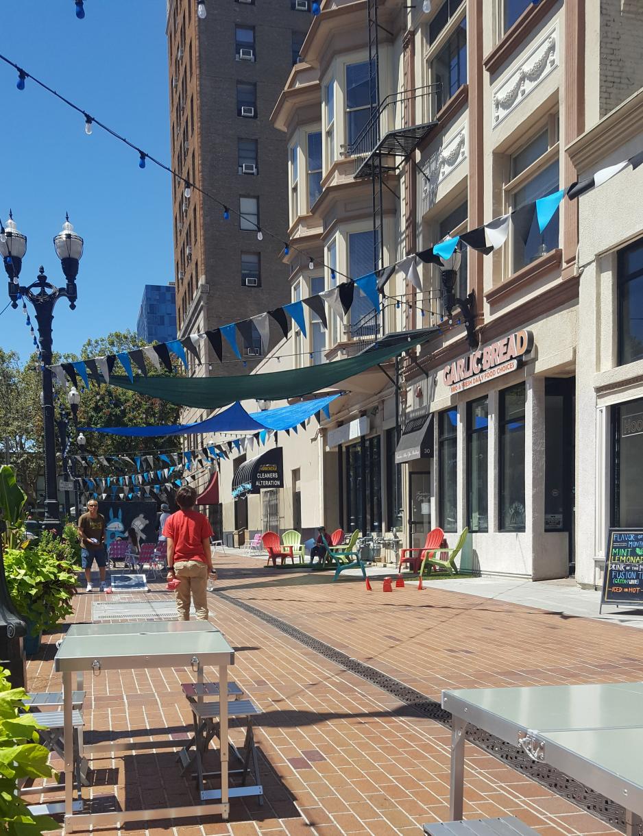 A photo of a mid-block passage with tables and chairs adjacent to restaurants. 