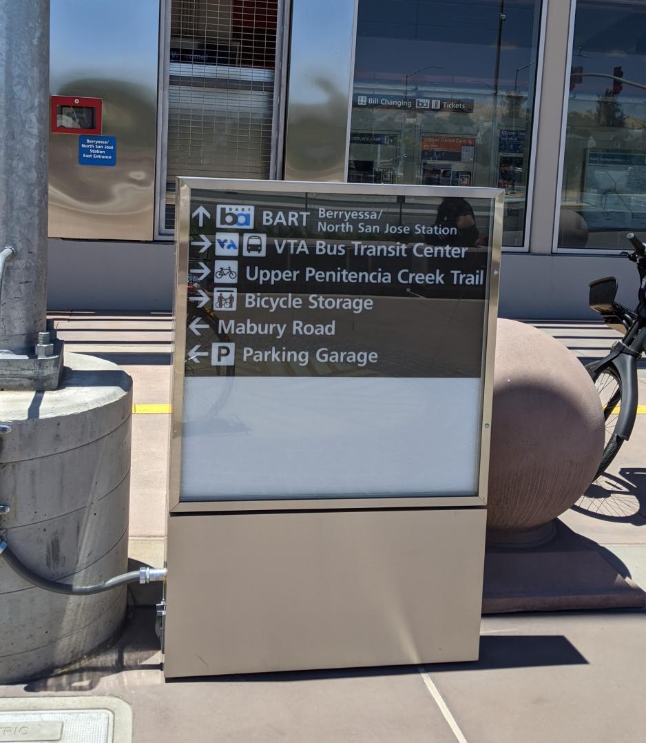 A photo of sign with direction arrows towards BART, Bus Transit Center, Parking Garage, Bike parking, and Major Roads.