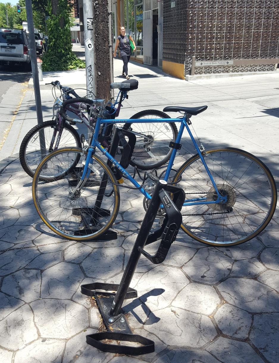 A photo of a bike rack with two bikes on a sidewalk.